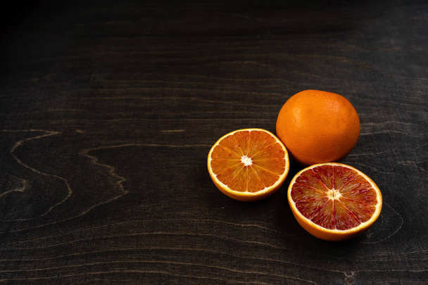A closeup photo of vibrant organic blood oranges on a dark background with copy space. - Foto, immagini
