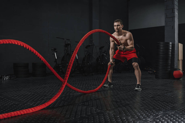 Jovem atleta fazendo exercício de cordas de batalha no ginásio crossfit
 - Foto, Imagem