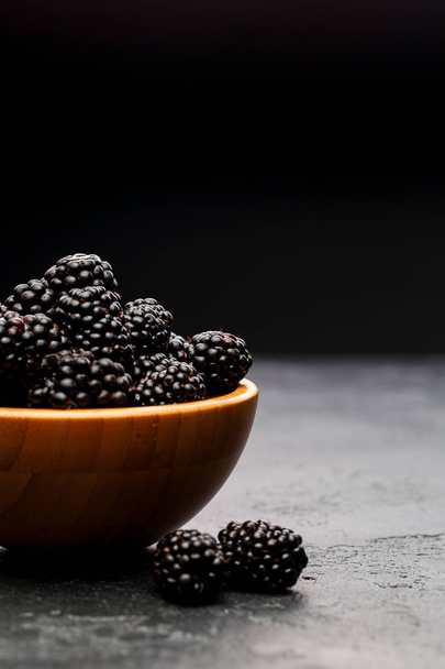Photo of blackberry in wooden cup on empty black background. - Fotografie, Obrázek
