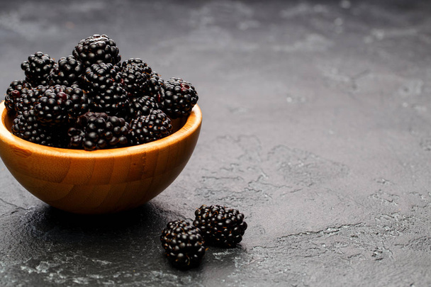 Zdjęcia blackberry w drewniany puchar na puste czarne tło. - Zdjęcie, obraz