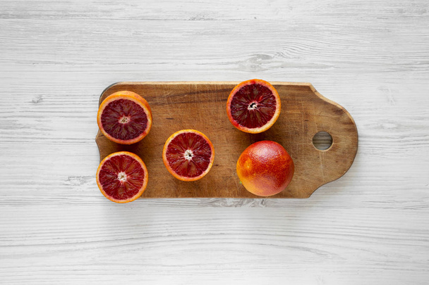 Blood oranges halved on rustic wooden board over white wooden ba - Foto, Imagen