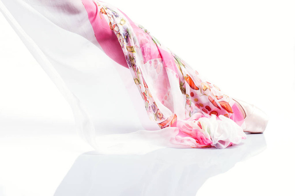 Τα πόδια της μπαλαρίνας στο Πουάν και με μεταξωτό κασκόλ σε λευκό προγρού - Φωτογραφία, εικόνα