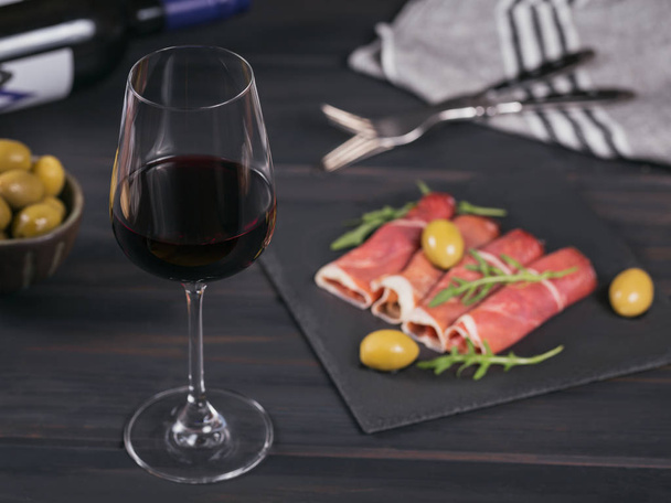 Glass of red wine with slices of cured ham or Spanish jamon serr - Valokuva, kuva