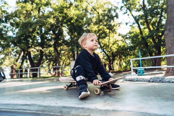 Young kid sitting in the park on a skateboard. - Foto, immagini