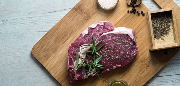 Крупним планом сире м'ясо стейка на крейдяній дошці зі спеціями
 - Фото, зображення
