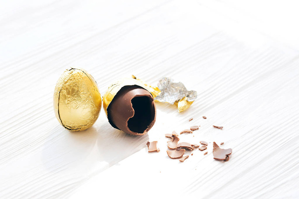 Happy Easter. Stylish Easter egg in golden foil and broken choco - Photo, Image