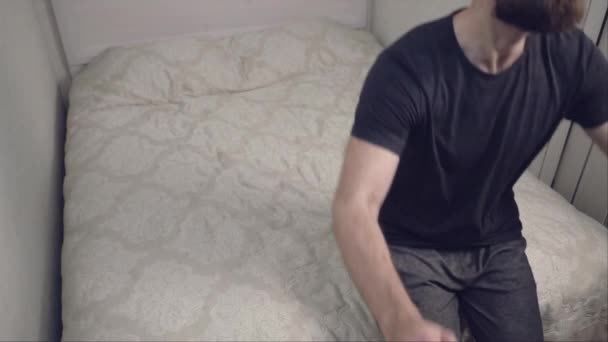 Bearded man falling on bed in slow motion - Materiał filmowy, wideo