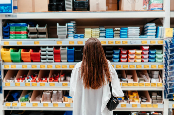 Vrouw kiest plastic dozen van verschillende kleuren voor de werkplaats - Foto, afbeelding