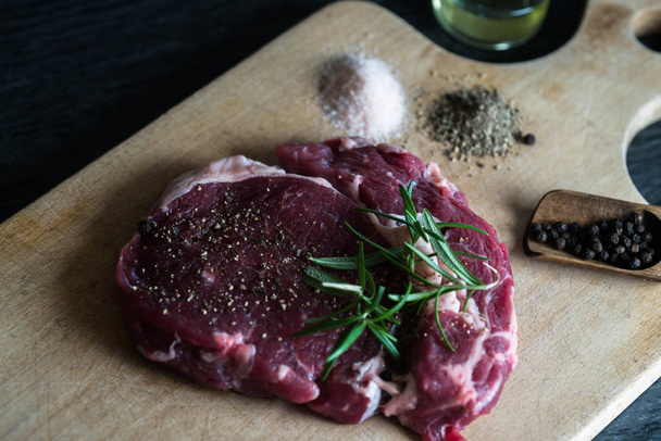 Morceau de viande de steak non cuite sur du tableau avec des herbes
 - Photo, image