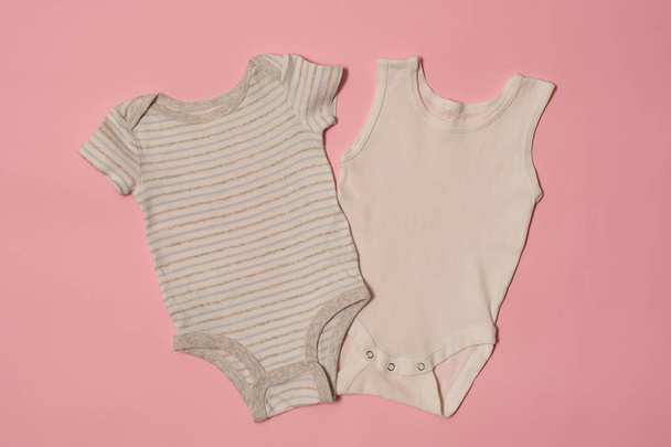 Body de bebé azul y blanco sobre fondo rosa. Concepto de moda
 - Foto, imagen