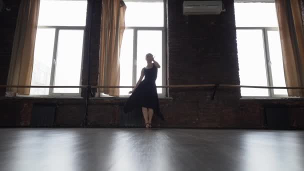 Chica en vestido negro hace divertido movimiento de baile cerca de la ventana en cámara lenta
. - Metraje, vídeo