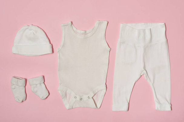 ピンクの背景の赤ちゃんファッション概念。キャップ、ボディー スーツ、パンツ、ソックス. - 写真・画像