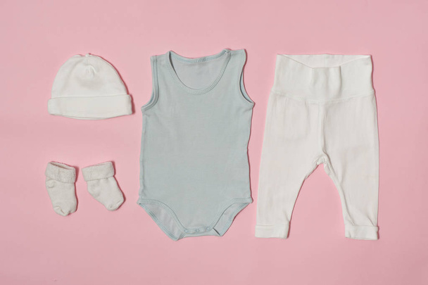 Baby fashion concept on a pink background. Cap, bodysuit, pants and socks. - Фото, изображение