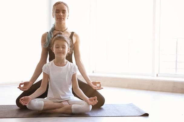 Mother and daughter practicing zen yoga in gym, space for text  - Foto, afbeelding