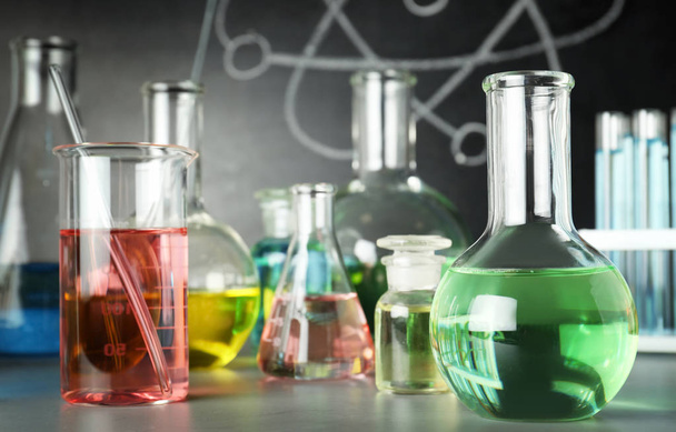 Laboratory glassware on table near chalkboard. Chemistry concept - Photo, Image