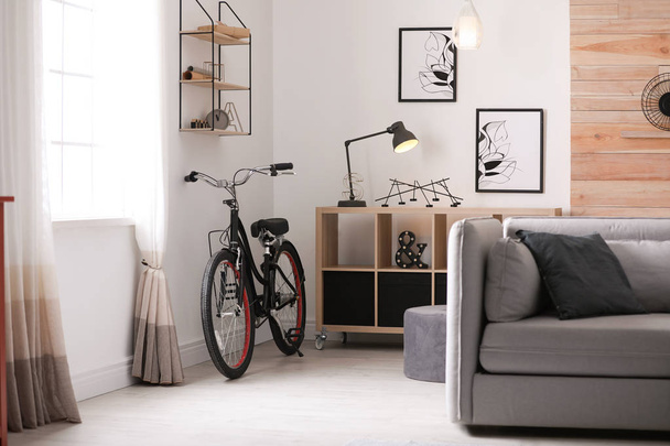 Soggiorno luminoso interno con comodo divano e bicicletta
 - Foto, immagini