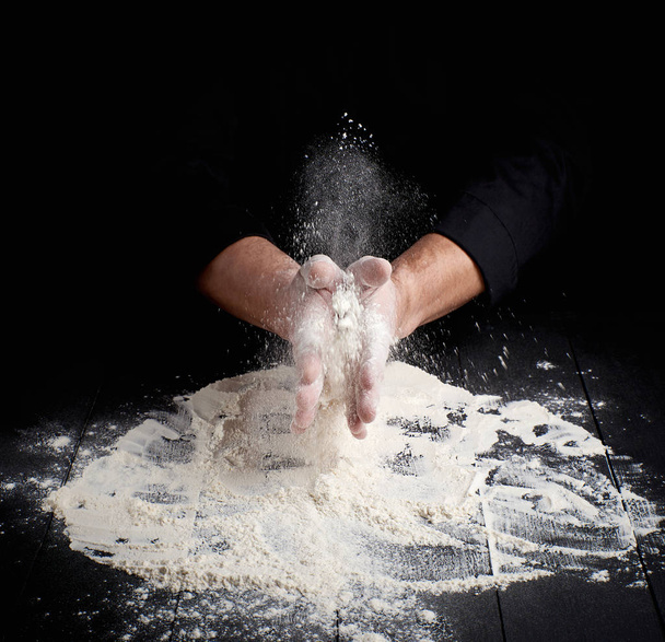 man's hands and splash of white wheat flour - Фото, зображення