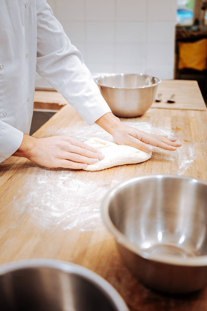Close up of baker kneading dough on the table in the morning - Фото, изображение