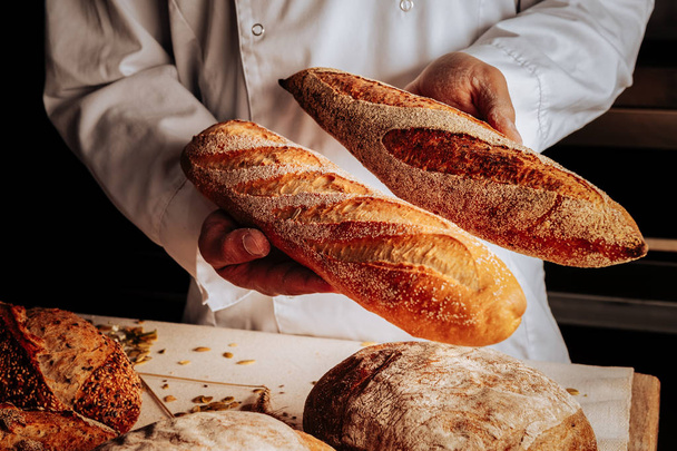Professional baker showing little wheat and rye baguettes - Foto, Imagem