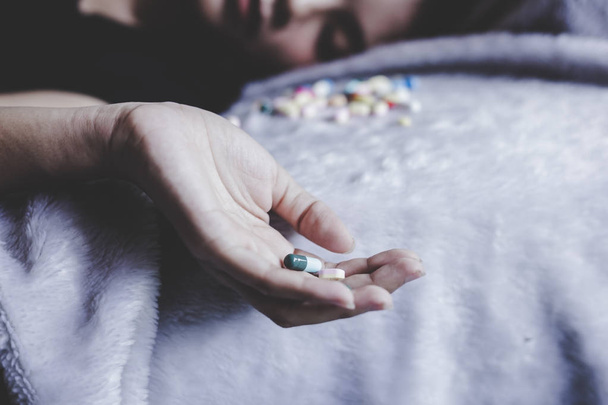 Woman suicide by taking overdose medicines at her house because young woman is major depressive disorder. Poor woman gets many problems of life and finding the way for ending her life by taking pills - Photo, Image