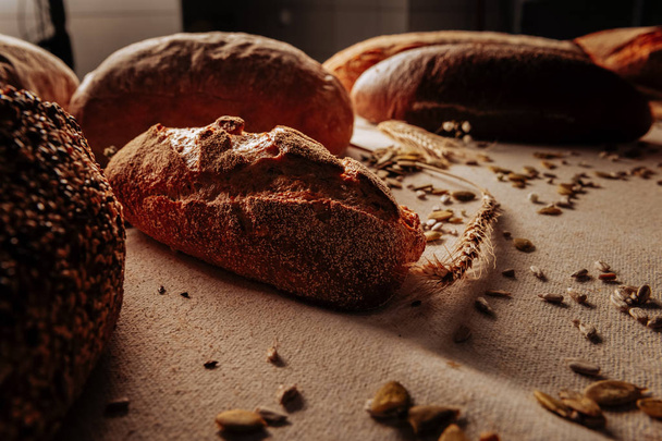 Dark rye gluten free bread lying near spikelet and seeds - Фото, изображение