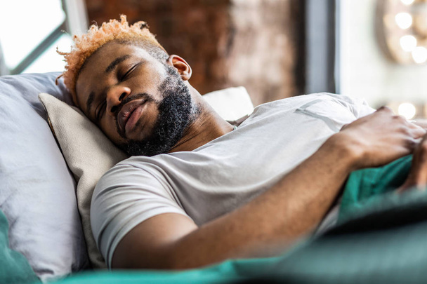 Handsome African American man lying on his bed - Photo, image