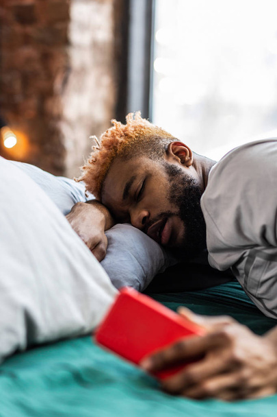 Gezellige goed uitziende man slapen met zijn telefoon - Foto, afbeelding