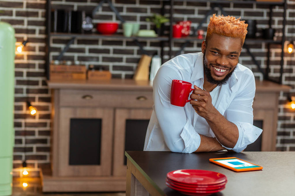 Χαρούμενη θετικός άνθρωπος στέκεται με ένα φλιτζάνι καφέ - Φωτογραφία, εικόνα