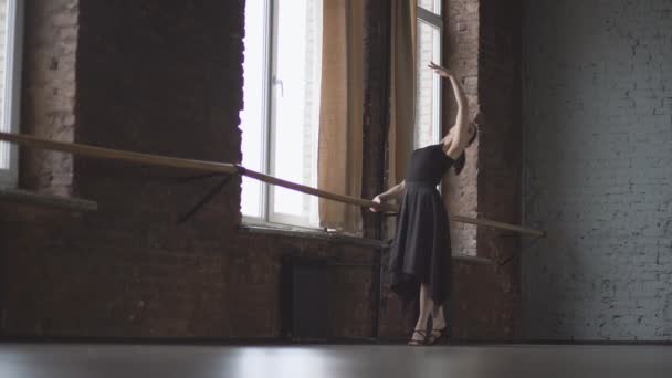 Жінка в чорній сукні робить балетний рух біля вікна в бальній кімнаті
. - Кадри, відео
