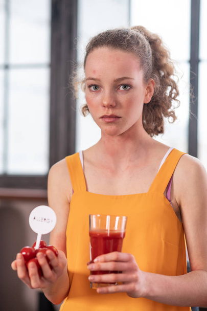 Calm and upset young woman staying with glass of tomato juice - Photo, image