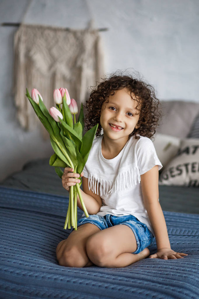 Happy mother's day, daughter gives a bouquet of tulips. African-American girl with a smile without teeth. - Foto, afbeelding