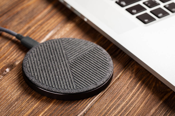 Wireless charging lies next to the computer on a stylish wooden  - Photo, Image