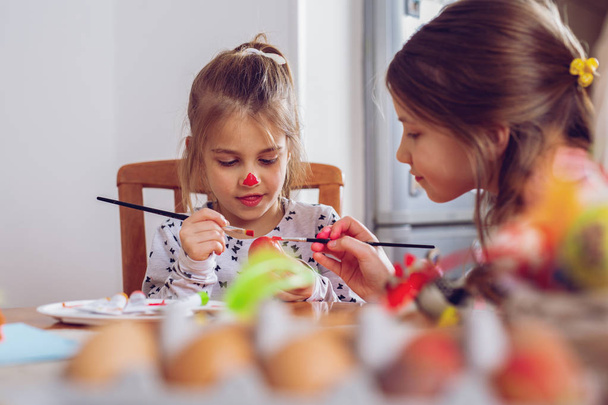 Счастливой Пасхи! Красивая девочка рисует пасхальные яйца
. - Фото, изображение