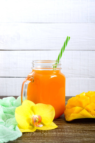 Mango smoothie bir cam ve ahşap arka plan üzerinde taze mango. Mango shake. Tropikal meyve kavramı. - Fotoğraf, Görsel