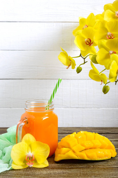 Mango smoothie in een glazen pot en verse mango op een houten achtergrond. Mango-shake. Tropisch fruit concept. - Foto, afbeelding