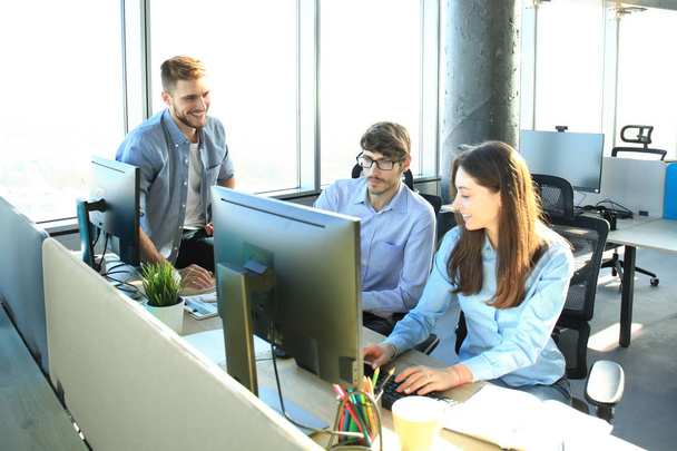 Jóvenes colegas en ropa casual inteligente trabajando mientras pasan tiempo en la oficina
. - Foto, Imagen