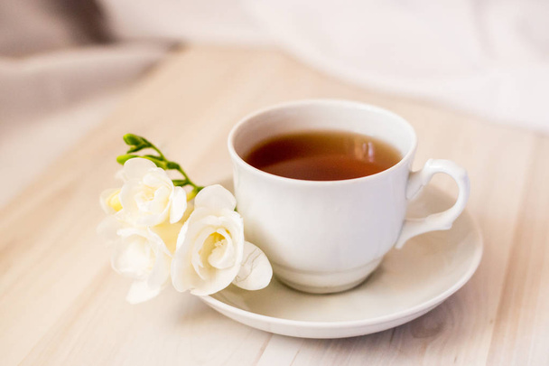 xícara de chá e flor freesia branca
 - Foto, Imagem