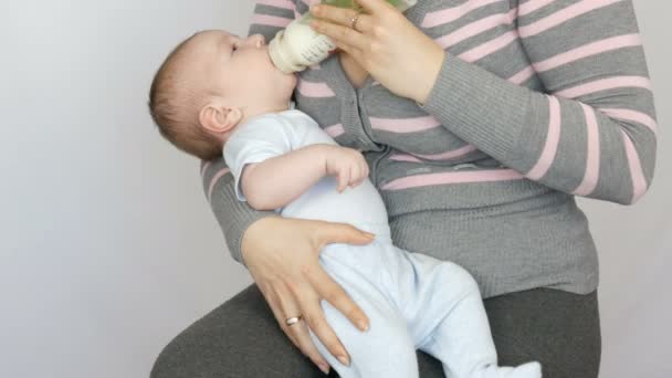 ein zwei Monate altes Neugeborenes liegt auf dem Arm der Mutter und saugt eine Brustwarze aus einer Milchflasche - Filmmaterial, Video