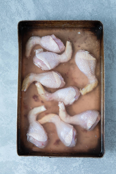 Bâtonnets de poulet saumurés dans une solution de saumurage dans un plateau et sur un fond gris. Vue du dessus du poulet en saumure
. - Photo, image