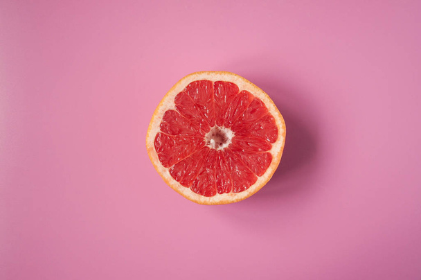 Цитрусовый грейпфрут на розовом фоне в порез. Экзотические фрукты. Витамин С
 - Фото, изображение