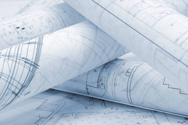 Скрученные архитектурные планы лежат на чертежной доске
 - Фото, изображение