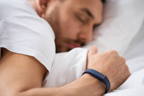 lähikuva miehestä, joka nukkuu aktiivisuusrannekkeen kanssa
 - Valokuva, kuva