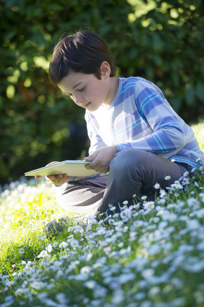 Child reading a book outdoors - Φωτογραφία, εικόνα