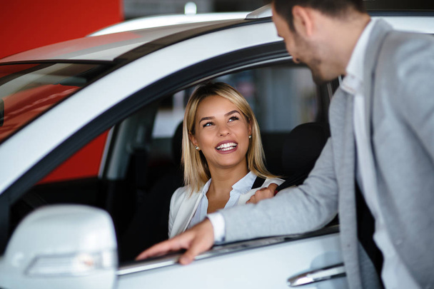 Successful happy businessman in a car dealership - sale of vehicles to customers - Foto, afbeelding