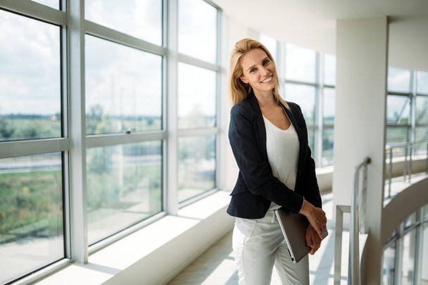 Successful business woman at work holding documents, standing near window in office - Foto, Imagem