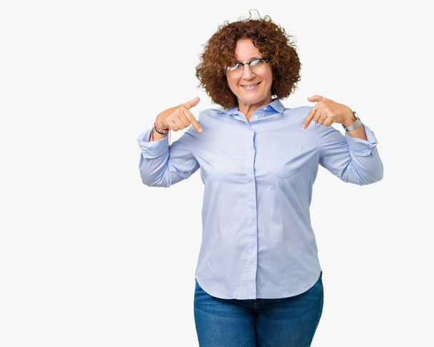 Beautiful middle ager senior businees woman wearing glasses over isolated background looking confident with smile on face, pointing oneself with fingers proud and happy. - Фото, зображення