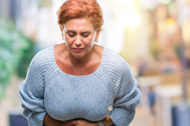 Korzystna starszy rude kaukaski kobieta sobie sweter zimowy nad na białym tle ręką na żołądek, bo niestrawność, bolesnej choroby, złe samopoczucie. Koncepcja ból. - Zdjęcie, obraz