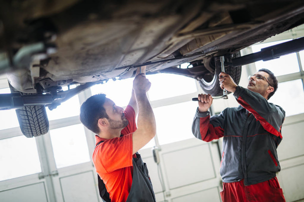 Car mechanics working at automotive service center together - Foto, Bild
