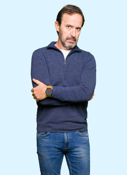 Μέση ηλικία όμορφος άνδρας φορώντας ένα πουλόβερ σκεπτικιστής και νευρικό, αποδοκιμασίας έκφραση στο πρόσωπο με σταυρωμένα τα χέρια. Αρνητικό πρόσωπο. - Φωτογραφία, εικόνα