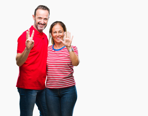 Středním věku hispánský pár v lásce izolované pozadí zobrazení a ukázal prsty číslo osm zároveň s úsměvem a spokojené. - Fotografie, Obrázek